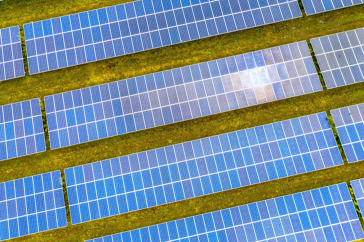 Große Solarpark mit zahlreichen blauen Solarmodulen auf grünem Feld, nachhaltige Energieerzeugung in Deutschland.