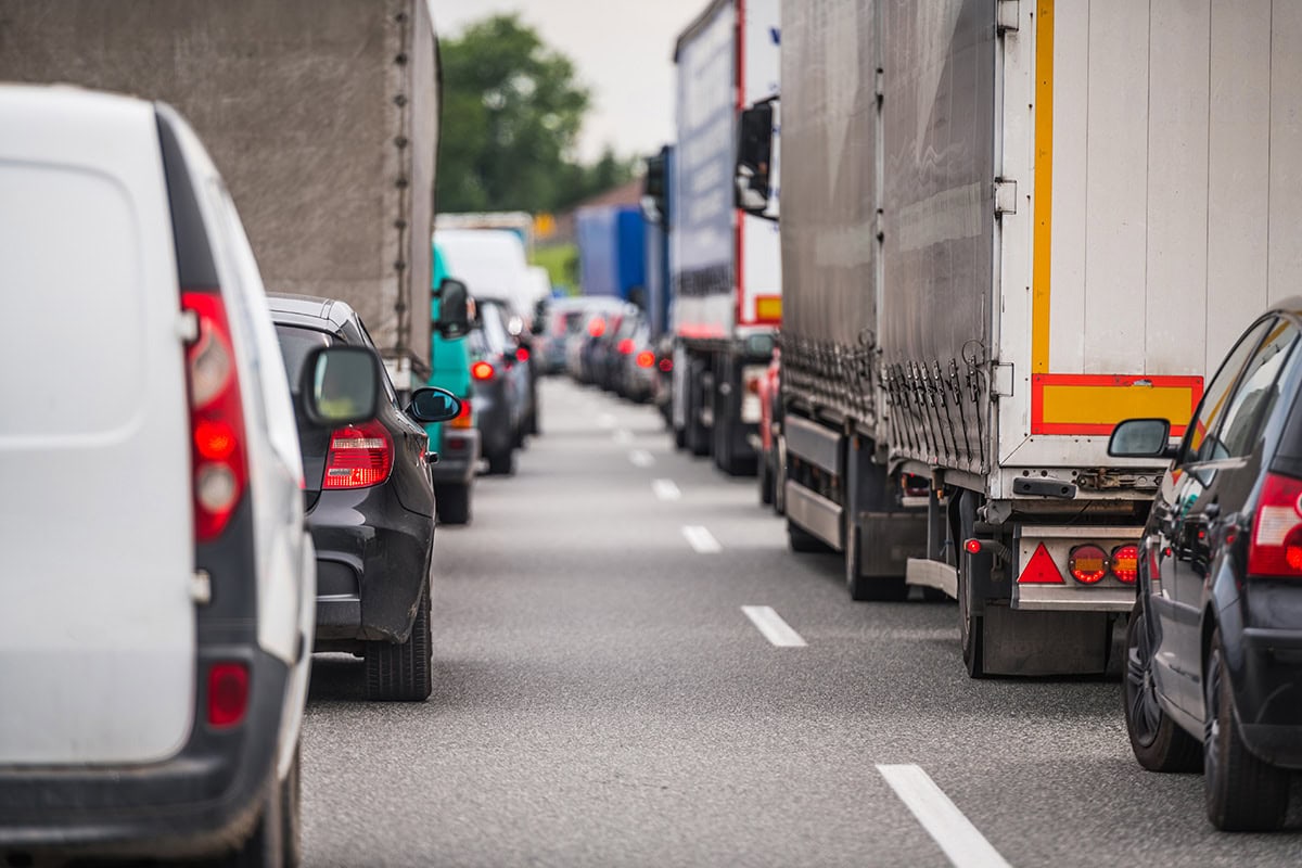 Stau auf einer Autobahn mit stehenden Fahrzeugen und LKWs im Verkehrsfluss.